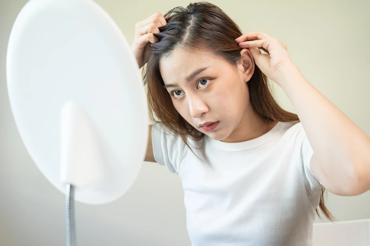 鏡で生え際を確認する女性