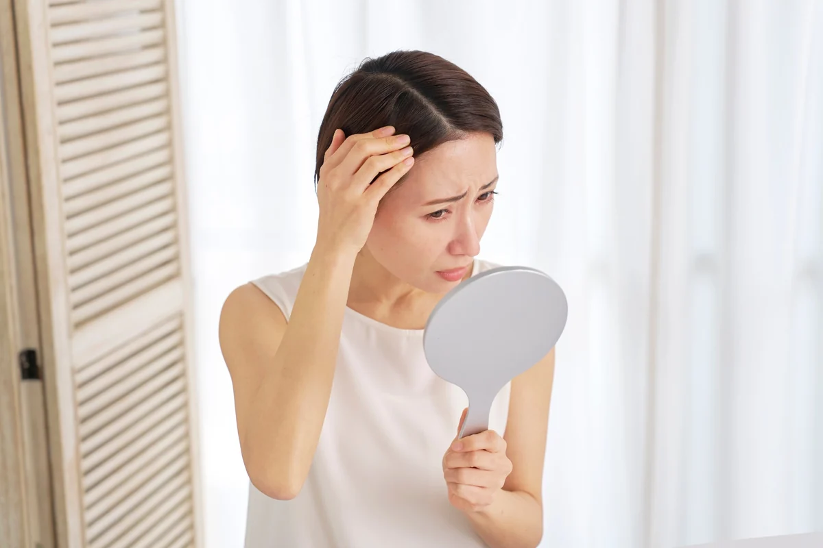 鏡で髪のボリュームを確認する女性